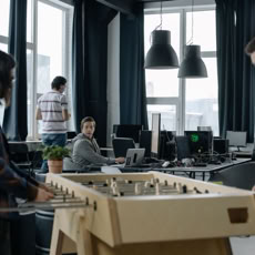 A modern office environment featuring a foosball table with employees engaging in teamwork.