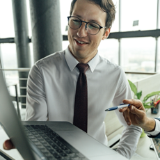 A businessman with glasses engaged in a meeting using a laptop in a modern office.