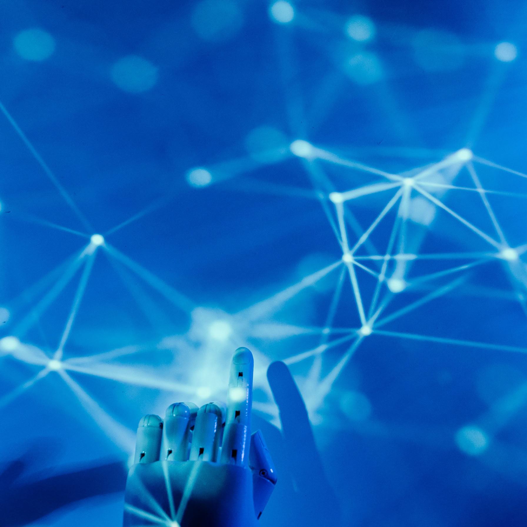 Futuristic robotic hand touching a digital network on a blue background.