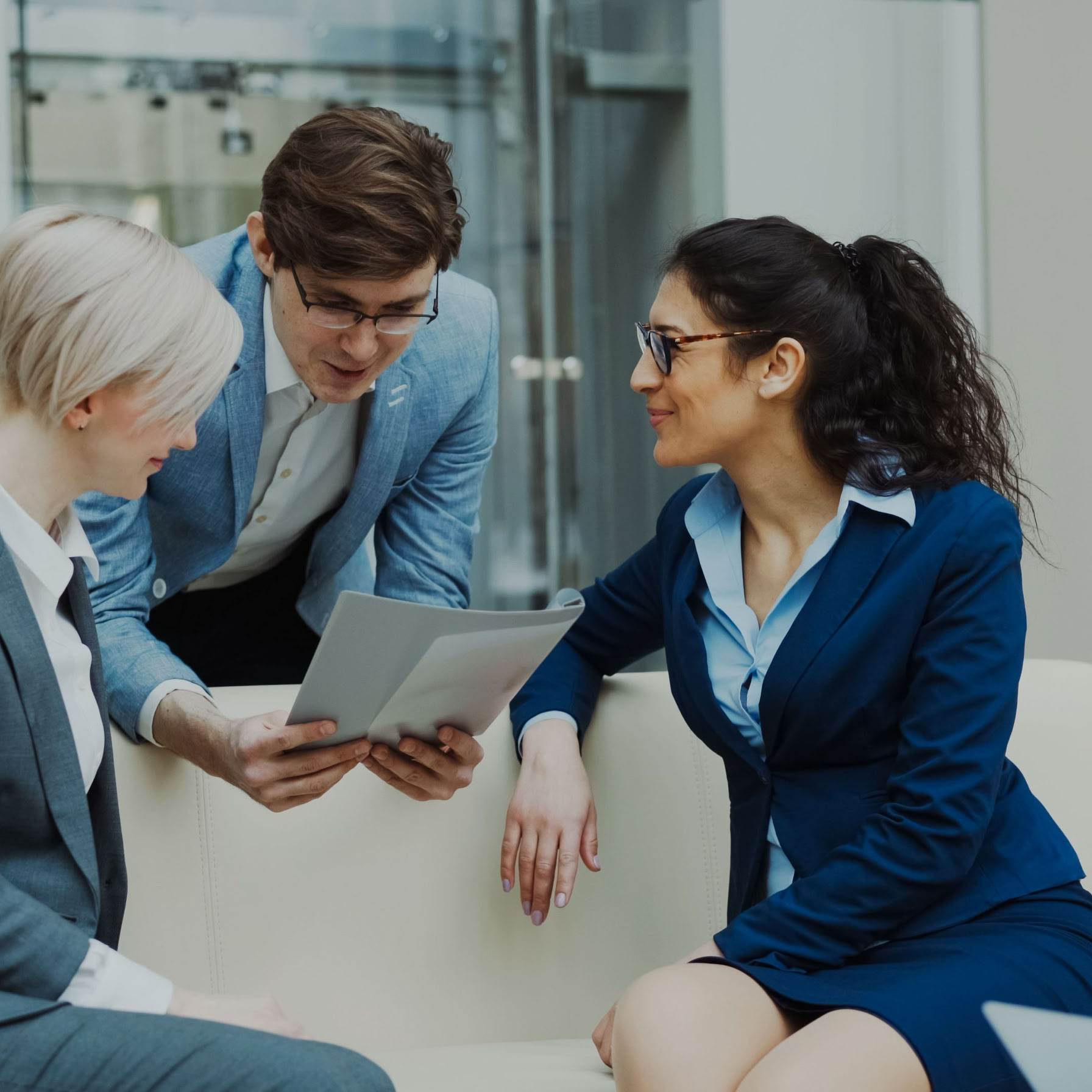 Three business professionals engaged in a meeting, collaborating over a tablet.